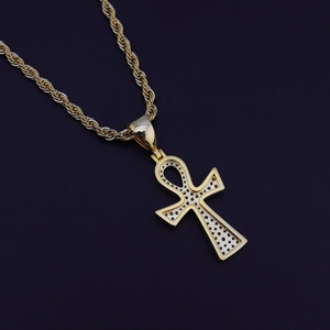 Vue détaillée du pendentif croix Ankh doré avec pierres noires et chaîne torsadée