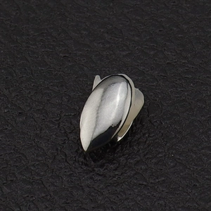 Close-up of polished silver single tooth grillz on a textured black jewelry cushion