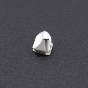 Polished silver single tooth grillz with sharp canine design on dark leather background