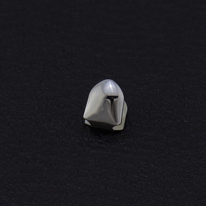 Close-up of polished silver single tooth grillz on a textured black background