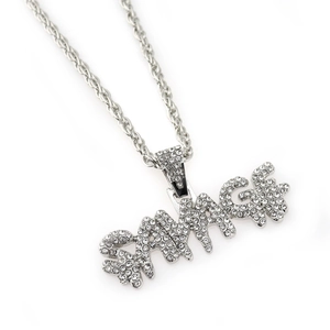 Macro detail of silver hip hop necklace with SAVAGE pendant and white rhinestones