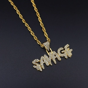 Detailed close-up of iced out SAVAGE pendant with gold rope chain on black texture