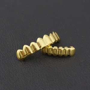 Detalle de los protectores dentales grillz de hip hop bañados en oro de 18K sobre cuero negro