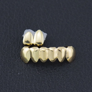 Polished gold-plated hip hop teeth grillz set with upper and lower pieces on black leather