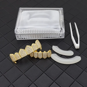 Close-up of hip hop gold grillz set with clear zircon stones and fitting accessories