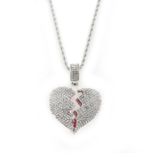 Macro view of iced out silver broken heart pendant with red accents and rope chain