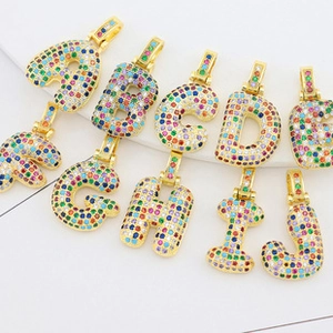 Close-up of hip hop necklaces featuring A-J gold pendants with rainbow colored zircon