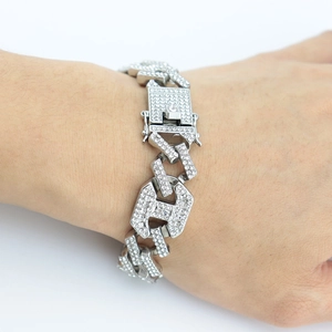 Vue macro du bracelet gourmette argenté orné de strass avec le détail du charme lettre H