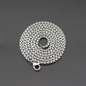 Détail d'un collier chaîne box en acier inoxydable enroulé avec un fermoir mousqueton