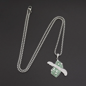Détail macro du pendentif dollar avec ailes et cristaux verts style hip hop chic