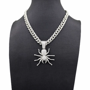 Macro detail of the iced-out silver spider pendant and chunky Cuban link chain necklace