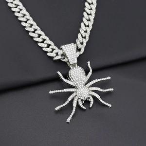 Macro view of iced out silver spider pendant on heavy Cuban link chain with white crystals