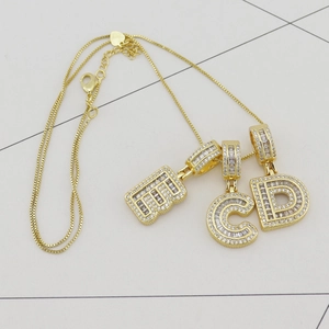 Détail de pendentifs lettres E, C, D en or avec zircons baguette et ronds sertis sur chaîne