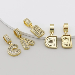 Gros plan de pendentifs alphabet en cuivre doré sertis de pierres de zircone