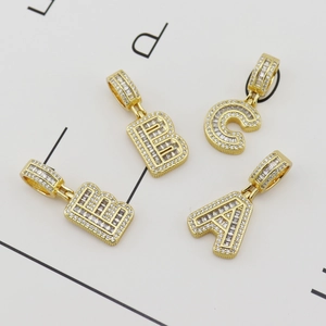 Détail de pendentifs alphabet en cuivre doré avec pierres de zircone micro-pavées