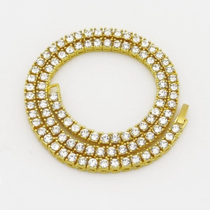 Macro shot of gold tennis chain showing round cubic zirconia stones and secure clasp