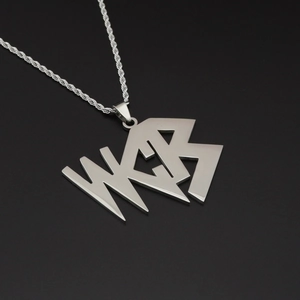 Détail macro du collier hip hop en acier titane avec pendentif lettre WCB et chaîne torsadée