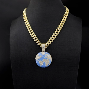 Close-up of hip-hop globe pendant with iced-out diamonds and blue enamel on gold cuban chain