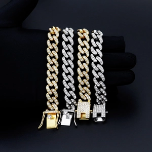 Détail de colliers maille cubaine 12mm avec cristaux micro-pave sur un fond noir sombre