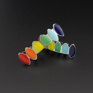 Close-up of hip-hop teeth grillz featuring colorful rainbow enamel on polished metal
