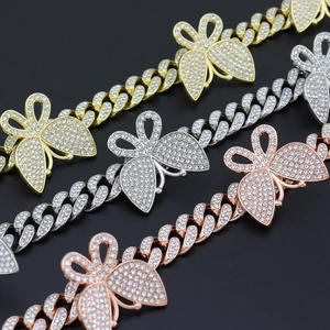 Gros plan détaillé des colliers cubains sertis de diamants avec pendentifs papillon en or, argent et rose