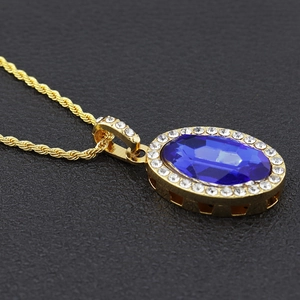 Détail macro d'un collier chaîne dorée avec un grand pendentif ovale en pierre bleue
