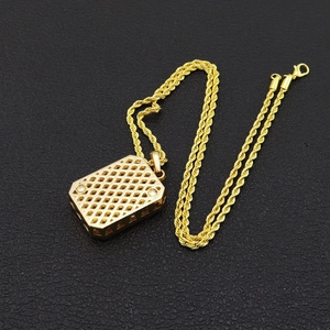 Pendentif rectangulaire doré avec maille torsadée sur fond noir pour style hip hop