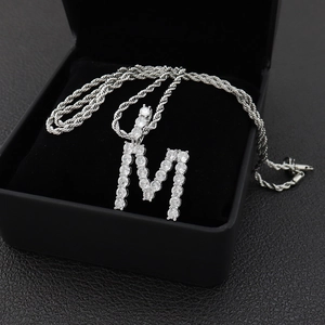 Vue macro du pendentif lettre M en argent avec zircons cubiques sur une chaîne de corde