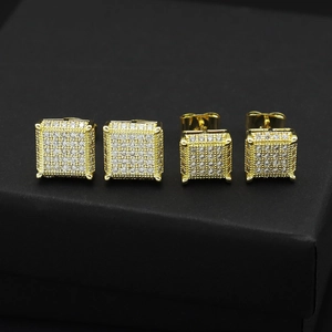 Macro shot of gold square zircon stud earrings set on a black textured jewelry box