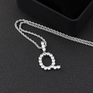 Gros plan du pendentif lettre Q argenté avec zircons sur une texture cuir noir