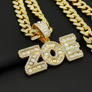 Détail macro de la chaîne cubaine dorée et pendentif ZOE glacé avec strass étincelants