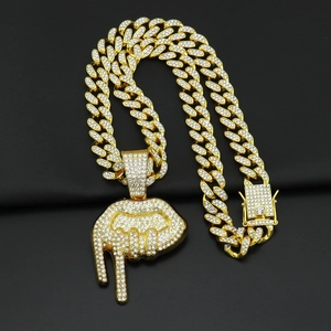 Gros plan d'une chaîne cubaine dorée avec strass et pendentif en forme de lèvres coulantes