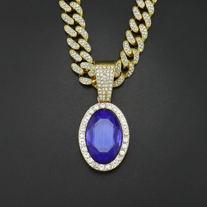 Macro shot of gold Cuban chain necklace with a large oval blue gemstone and rhinestones