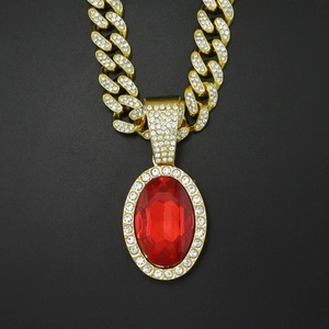 Macro view of gold-plated hip hop necklace with red gemstone and iced out Cuban chain
