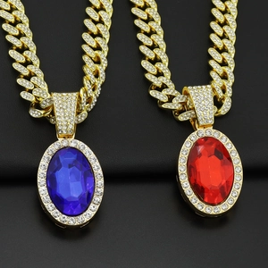 Close-up of hip hop gold Cuban link necklace featuring large oval red and blue stones