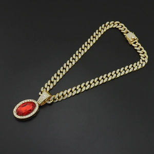 Detail of hip-hop gold Cuban link necklace with iced-out crystals and red oval gemstone