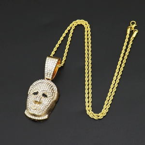 Macro shot of gold hip-hop mask pendant with white rhinestones and a thick rope chain