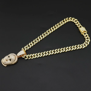 Close-up of hip-hop mask pendant and gold cuban link chain with white zircons