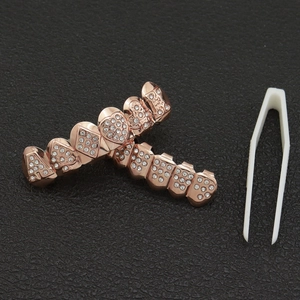 Detail of rose gold hip hop grillz set with sparkling rhinestones and tweezers