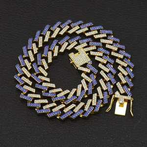 Dettaglio ravvicinato della catena cubana da 15mm dorata con strass blu e bianchi su nero