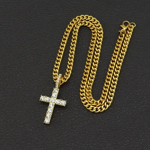 Close-up of gold cuban chain and iced out cross pendant with sparkling crystals