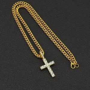 Macro shot of gold-plated iced-out cross pendant with sparkling crystals and cuban chain