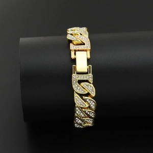 Macro shot of gold-tone Cuban chain bracelet with white rhinestones and a folding clasp