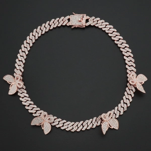 Détail de la chaîne cubaine papillon en or rose sertie de zircons sur fond noir mat