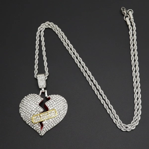 Macro del ciondolo a cuore spezzato con strass scintillanti e dettaglio cerotto dorato