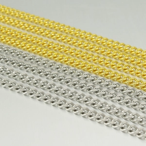 Détail des chaînes Cuban de 5 mm polies en or et argent disposées en lignes parallèles