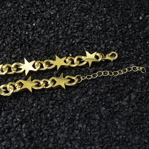 Détail d'un bracelet gourmette doré avec breloques étoiles et fermoir mousqueton réglable