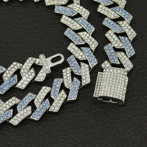 Détail d'une chaîne cubaine de 15 mm avec diamants roses et bleus sur fond texturé noir