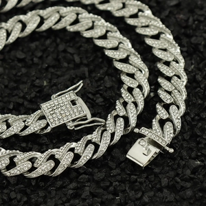 Macro shot of iced-out Cuban chain with square clasp on black stones background
