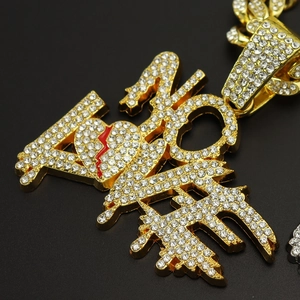 Close-up of gold iced-out ALONE letter pendant with broken red heart on Cuban chain